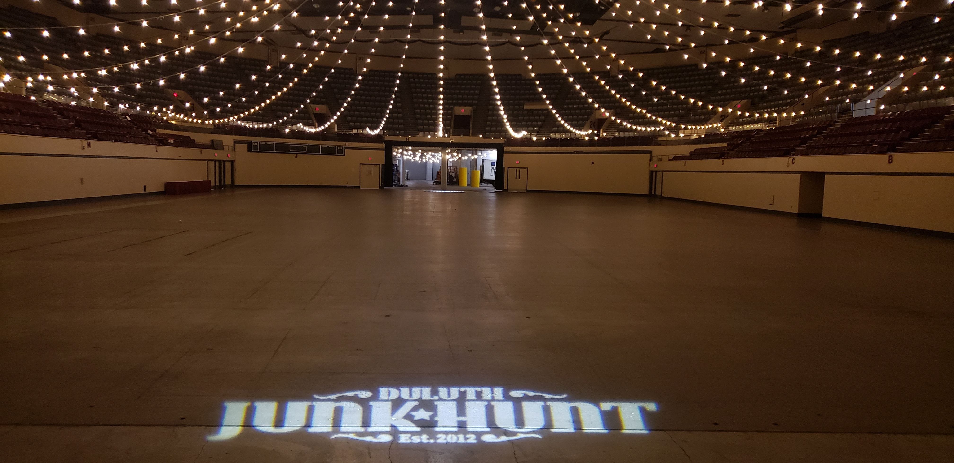 Tons of bistro hang in the air over the decc arean floor, a junk hunt logo is projected on the floor.