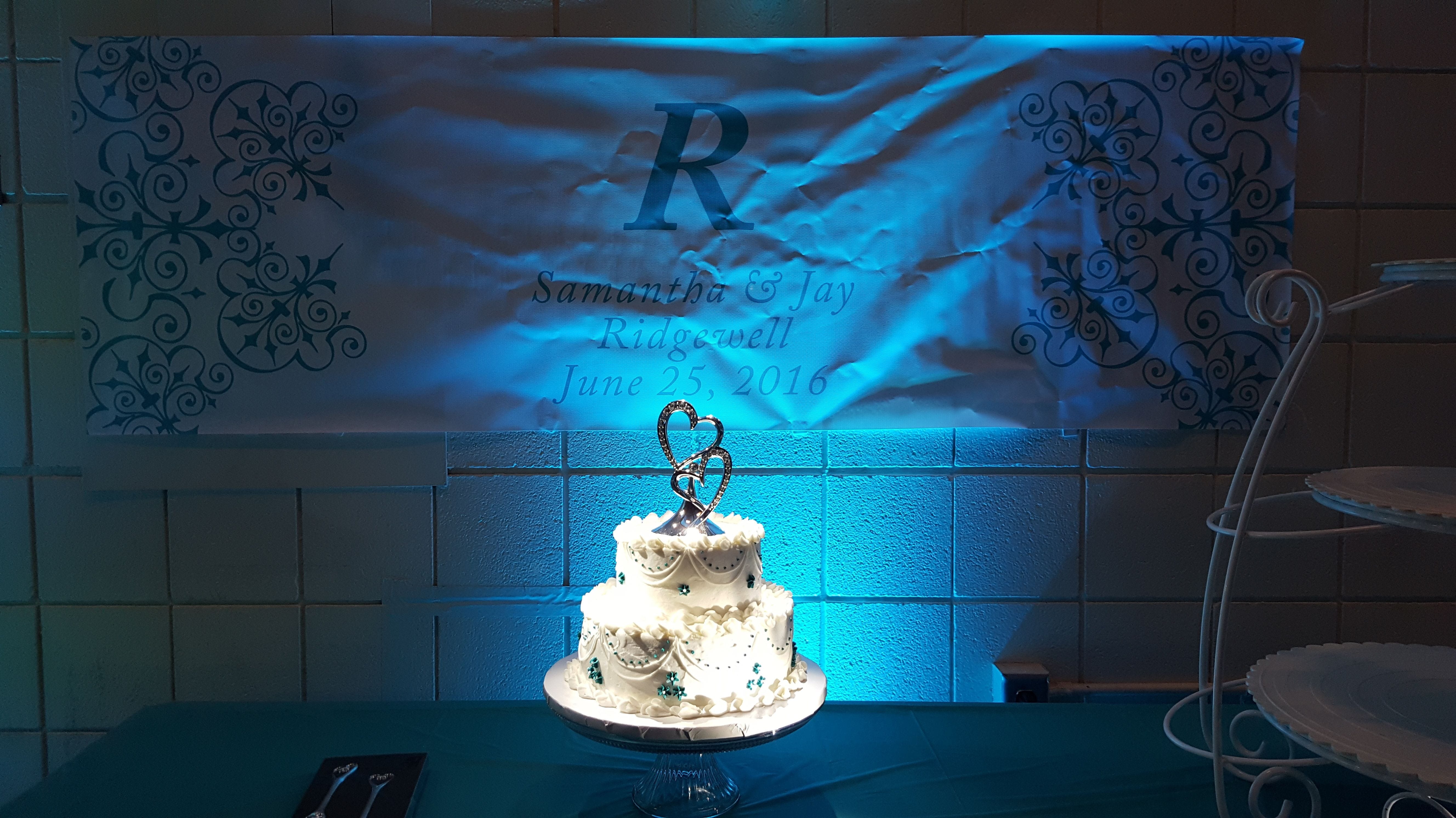 a Pin Spot lights a wedding cake with teal up lighting behind it by Duluth Event Lighting