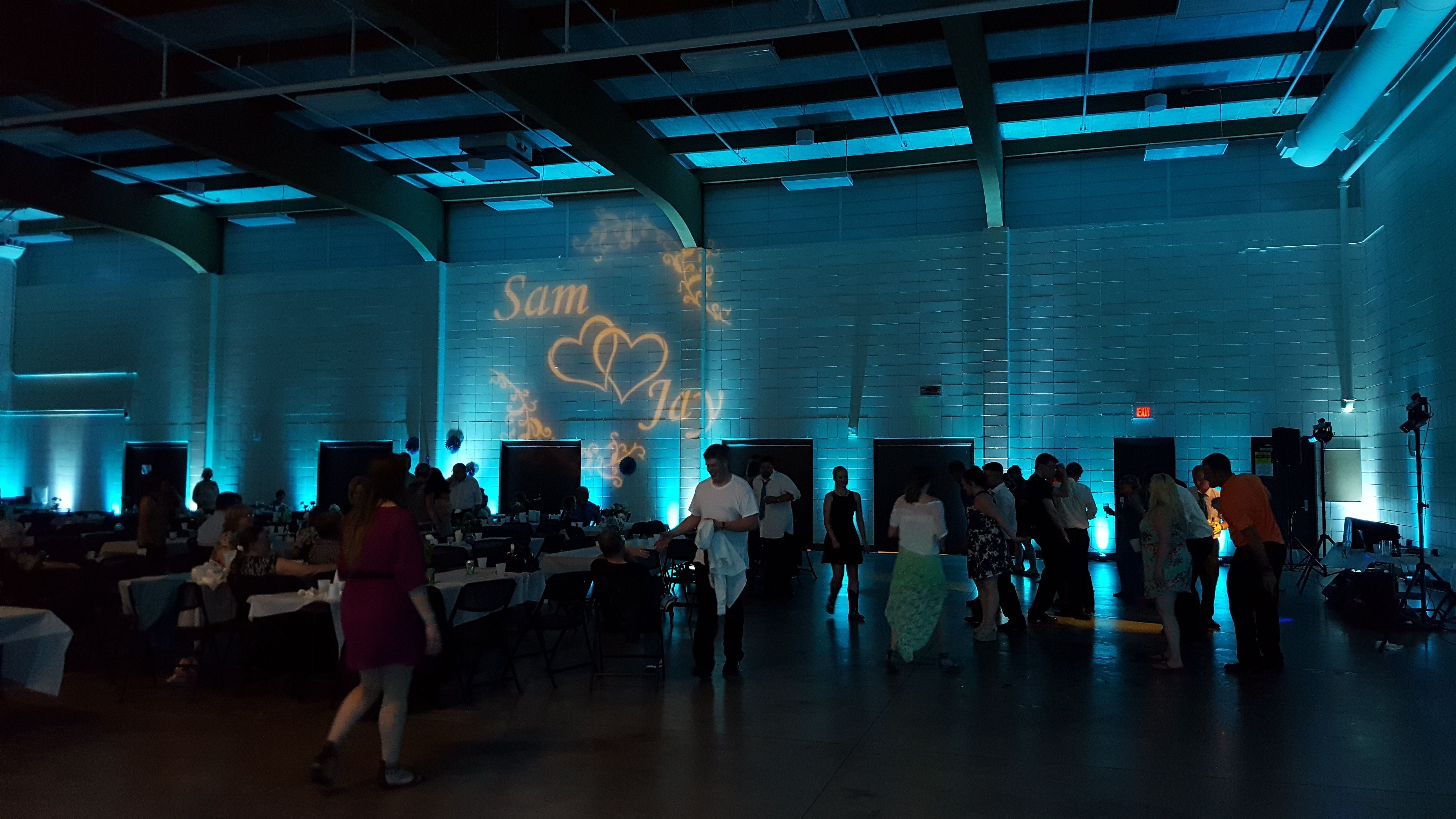 Duluth Armory wedding lighting by Duluth Event Lighting. Up lighting in teal. and a wedding monogram