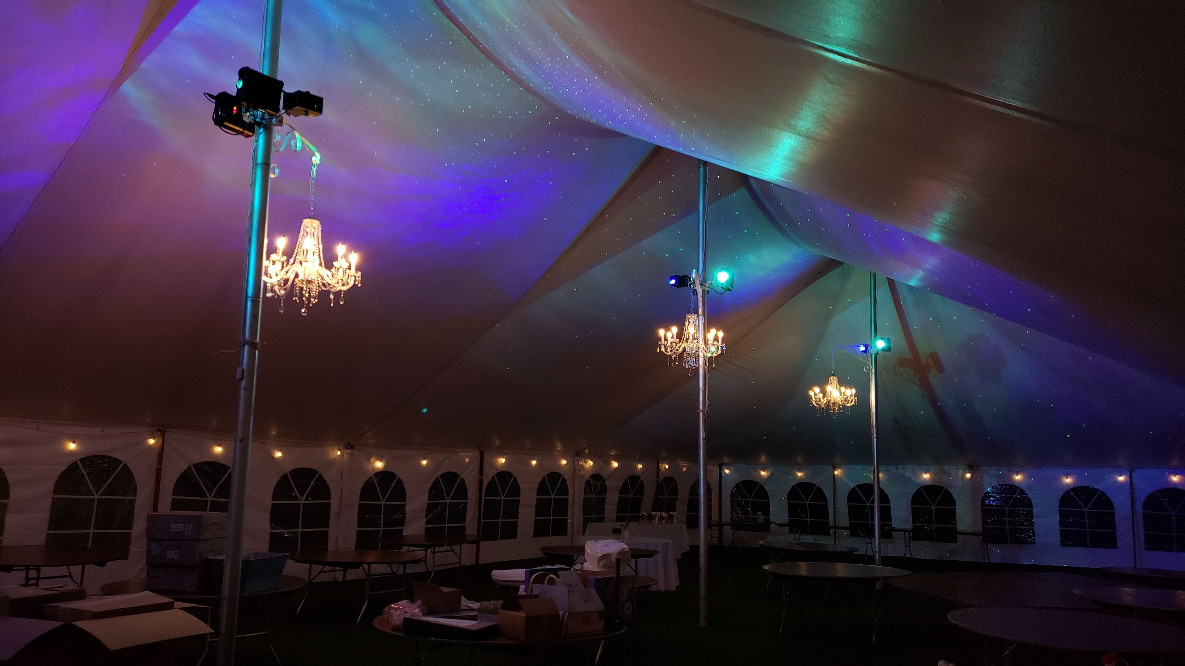 Tent wedding lighting. four chandeliers with perimter bistro. Stars and Northern Lights dance on the tent ceiling.