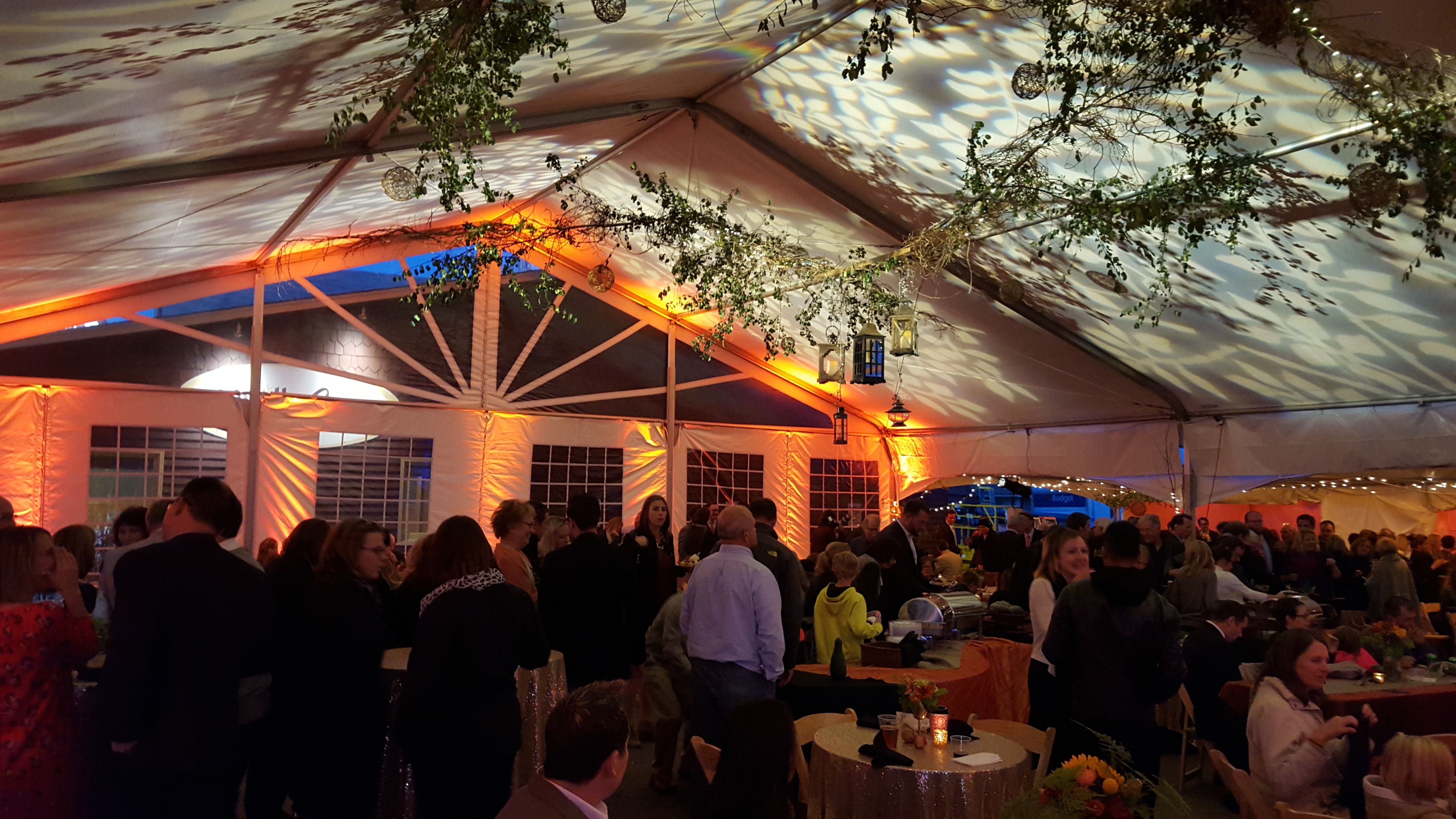 A spring themed wedding in a tent. Leaf gobos on the ceiling with orange up lighting.